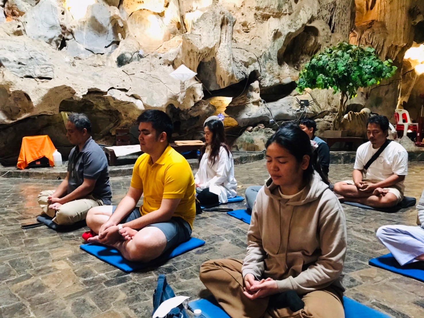 ผู้ปฏิบัติธรรมนั่งขัดสมาธิหลับตาภาวนาภายในถ้ำหินปูน